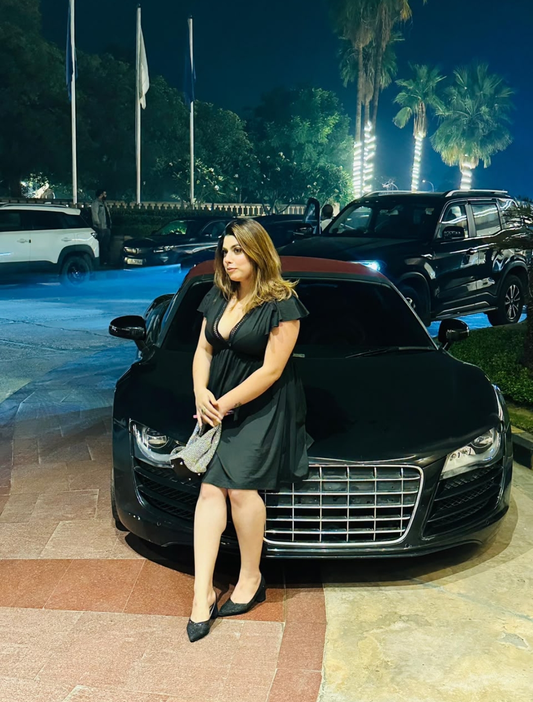 Guest portrait beside luxury car at night
